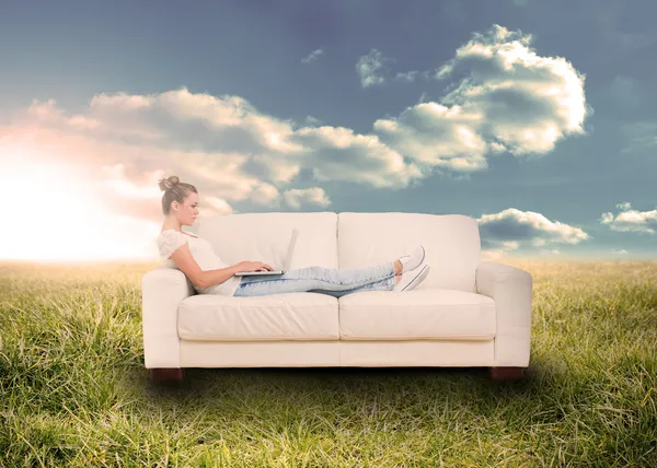 Woman using laptop on couch in field — Stock Photo, Image