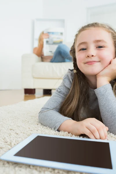 Szczęśliwa dziewczyna z jej komputera typu tablet i jej matka, czytania gazety — Zdjęcie stockowe