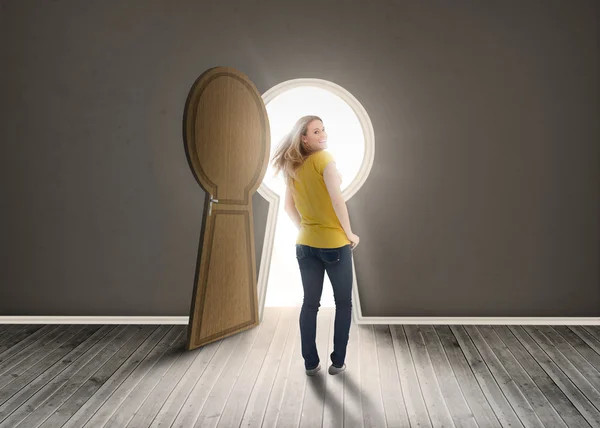 Vrouw lopen naar sleutelgat vormige deuropening met licht — Stockfoto