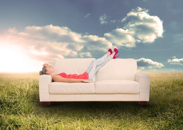 Woman relaxing on couch in field — Stock Photo, Image