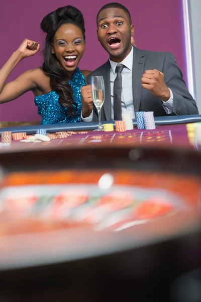 Couple sitting cheering at roulette wheel — Stock Photo, Image