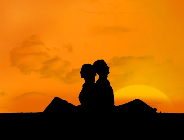 Silhouette of couple relaxing under a sunset — Stock Photo, Image