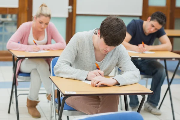 Writing students at desks in a classroom — Stock Photo, Image