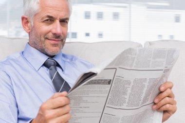 Smiling businessman holding a newspaper clipart