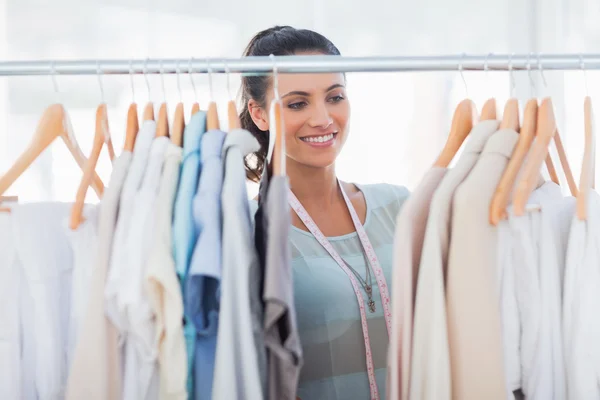 Attractive fashion designer looking at clothes — Stock Photo, Image