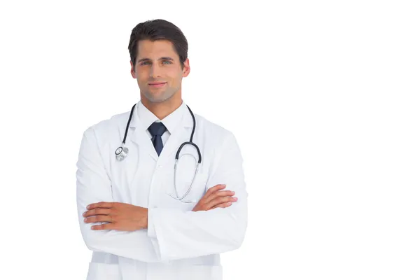 Médico atraente sorrindo com os braços cruzados — Fotografia de Stock