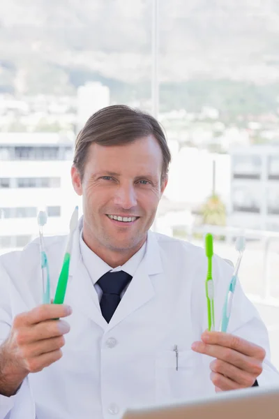 Cheerful doctor holding two toothbrushes — Stock Photo, Image