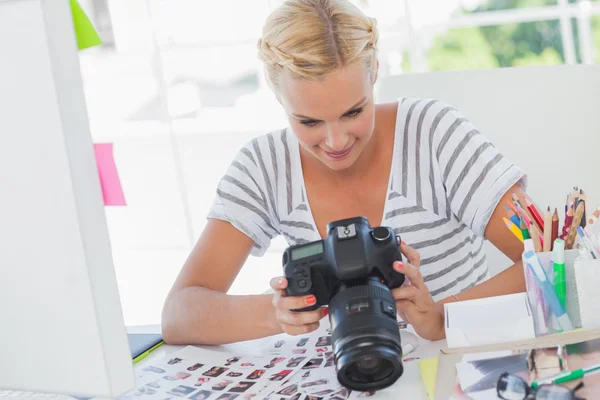 Blonde photo editor looking at a digital camera — Stock Photo, Image