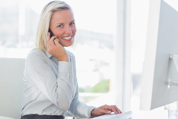 Молодая деловая женщина по телефону улыбается в камеру — стоковое фото