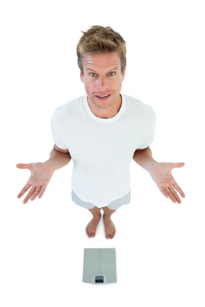 Man gesturing in front of a weighing scale — Stock Photo, Image