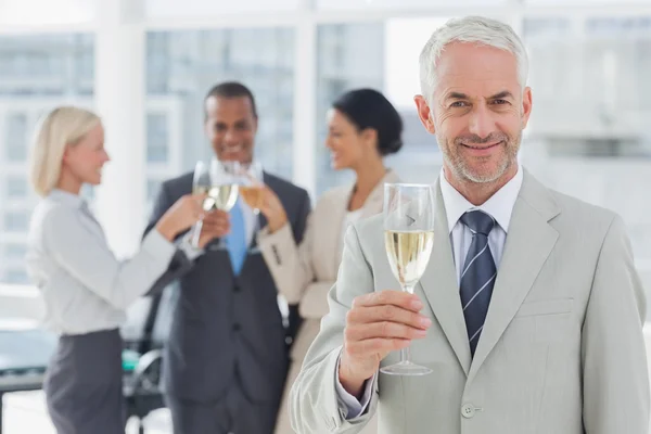 Empresario sonriendo a la cámara sosteniendo champán — Foto de Stock
