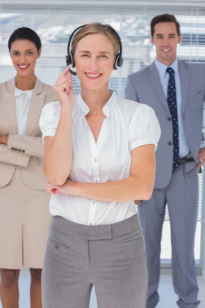 Cheerful woman with headset standing in front of business — Stock Photo, Image