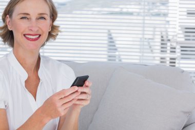 Smiling businesswoman using her mobile phone clipart