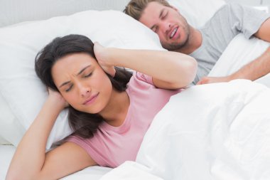 Woman covering ears while her husband is snoring clipart