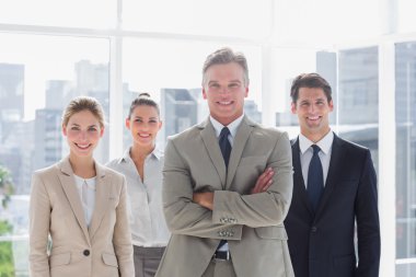 Boss with his arms folded standing with smiling colleagues behind clipart