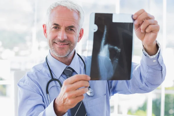 Médico sonriente sosteniendo una radiografía — Foto de Stock