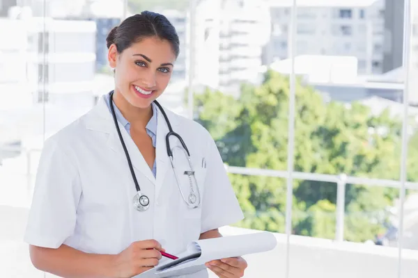 Médico sorrindo e segurando prancheta e caneta — Fotografia de Stock