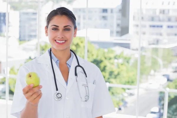 Médecin souriant tenant une pomme verte — Photo