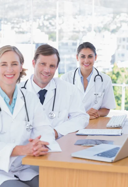 Веселые врачи позируют за своим столом — стоковое фото