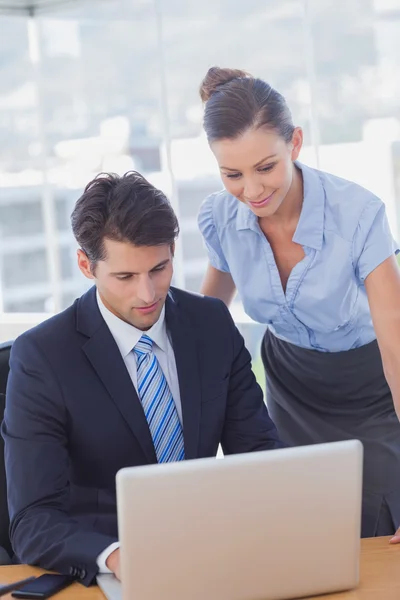 Zakelijke glimlachend en werken samen met een laptop — Stockfoto