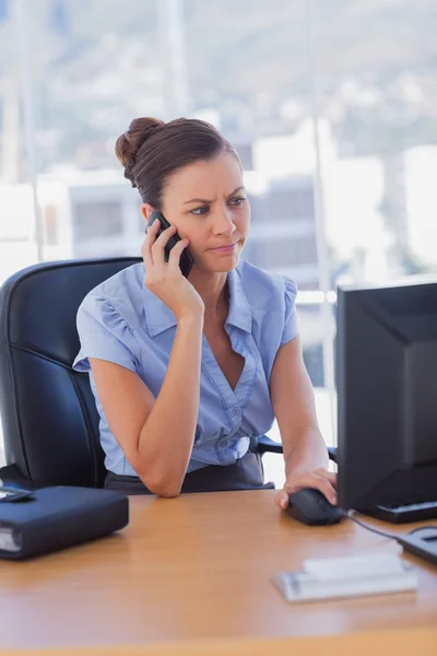 Konzentrierte Geschäftsfrau, die am Computer arbeitet und telefoniert — Stockfoto