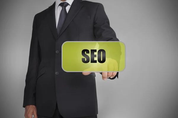 Businessman selecting green tag with the word seo written on it — Stock Photo, Image