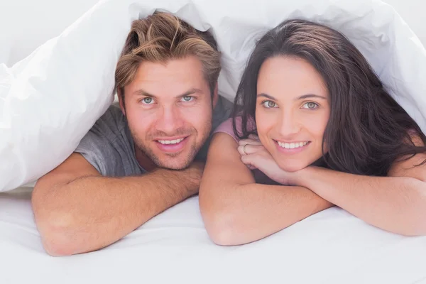 Fröhliches Paar unter der Bettdecke — Stockfoto