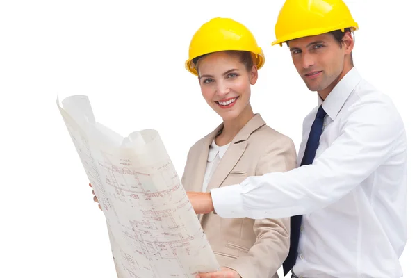 Architects with construction plan and yellow helmets — Stock Photo, Image