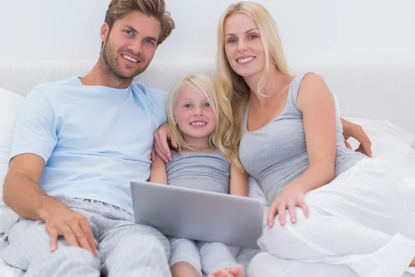 Famille utilisant un ordinateur portable au lit — Photo