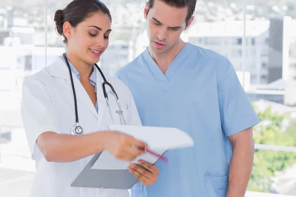 Doctor and surgeon going over notes on clipboard — Stock Photo, Image
