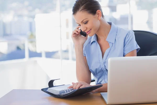 Glückliche Geschäftsfrau telefoniert mit ihrem Handy und schaut in Tagebuch — Stockfoto