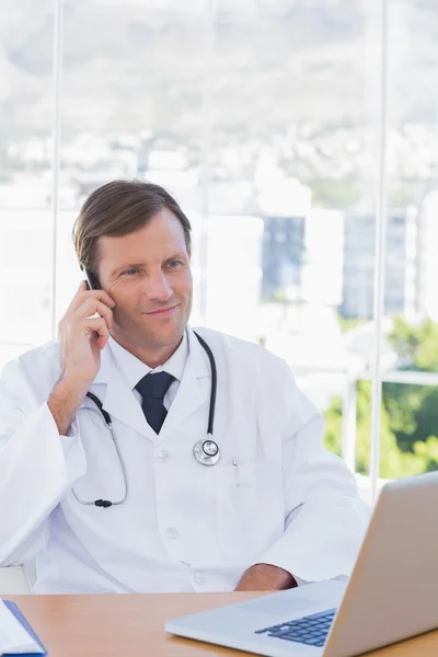 Médecin joyeux téléphonant dans son bureau — Photo