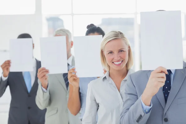 Business team covering face with white paper except for one woman — Stock Photo, Image