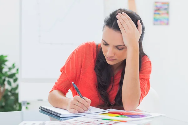 Diseñadora cansada sosteniendo su cabeza mientras dibuja —  Fotos de Stock