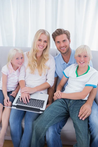 Leende familj med laptop i deras vardagsrum — Stockfoto