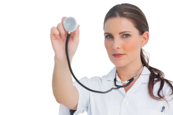 Serious nurse holding up stethoscope — Stock Photo, Image