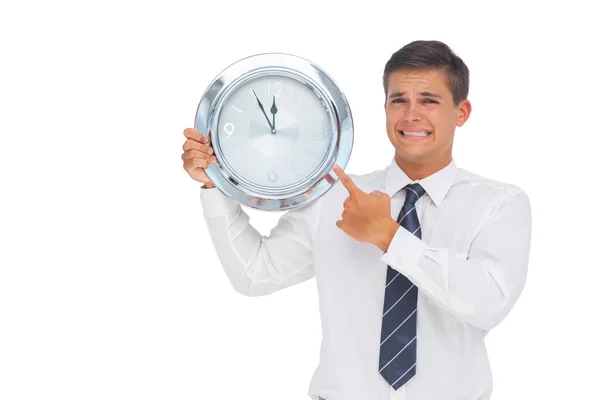 Homem de negócios ansioso segurando e mostrando um relógio — Fotografia de Stock