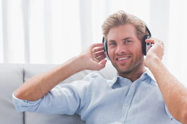 Man lyssnar på musik med hörlurar i vardagsrummet — Stockfoto