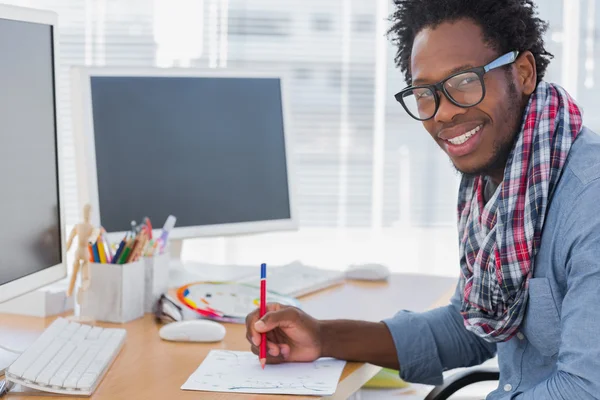 Lachende ontwerper tekenen iets met een rood potlood — Stockfoto