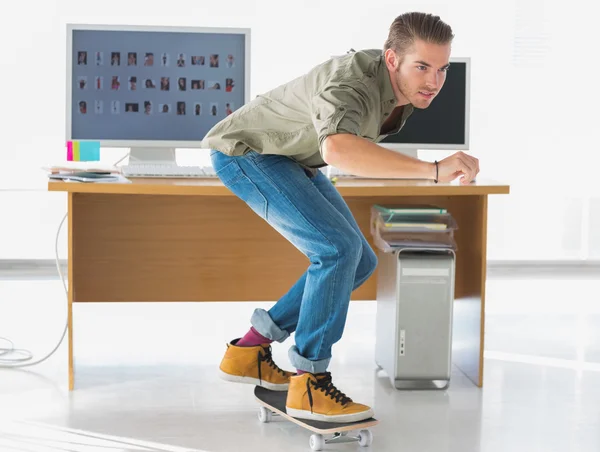 Красивый работник катается на коньках через офис — стоковое фото