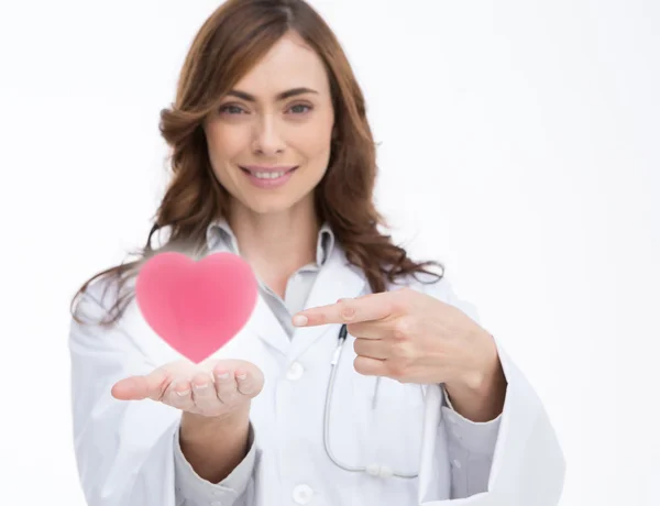 Médico segurando e apontando para um coração rosa — Fotografia de Stock