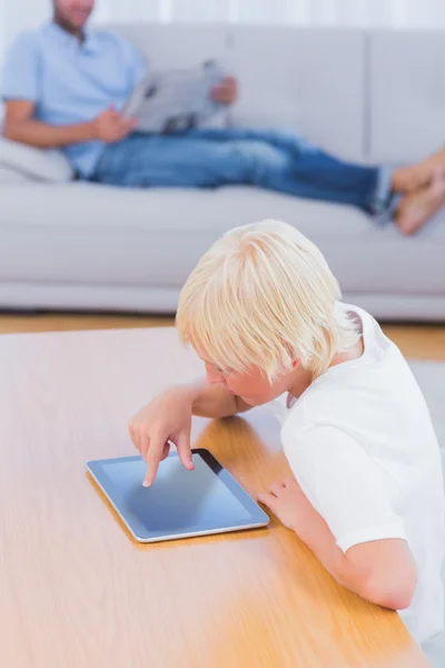 Jongen met behulp van Tablet PC aan tafel in de woonkamer — Stockfoto