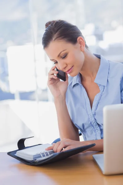 Gelukkig zakenvrouw kijken naar haar dagboek en bellen — Stockfoto