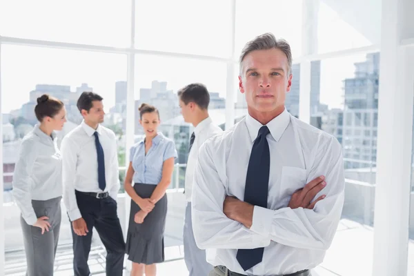 Serious boss with arms folded standing in a modern office — Stock Photo, Image