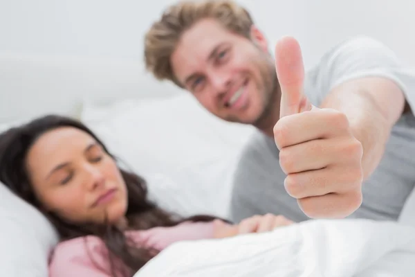 Mann gibt Daumen hoch, während seine Frau schläft — Stockfoto