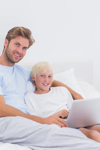 Retrato de un padre guapo y su hijo usando una computadora portátil —  Fotos de Stock