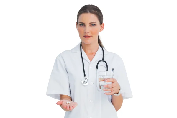 Enfermera sonriente sosteniendo medicina y vaso de agua —  Fotos de Stock