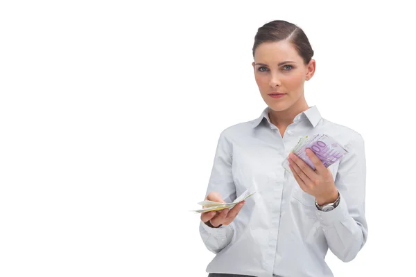 Businesswoman holding wads of cash and looking at camera — Stock Photo, Image
