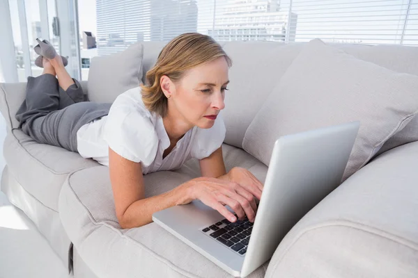 Businesswoman lying on couch and using laptop — Stock Photo, Image