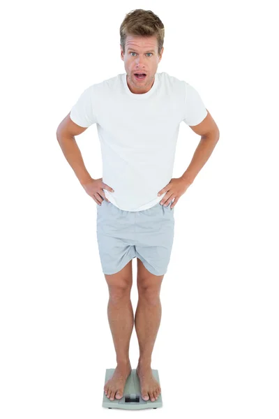 Shocked man standing on a weighing scale — Stock Photo, Image